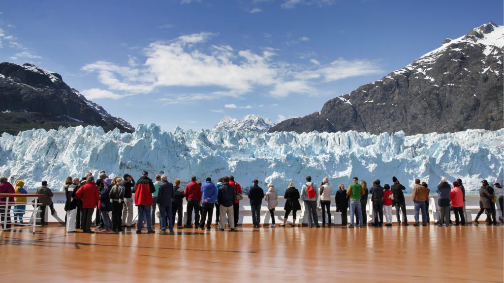 passengers on the deck of a cruise ship looking at a glacier in Alaska