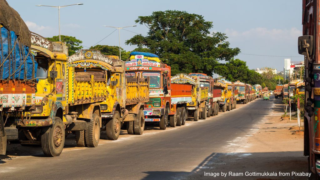 goods carrier trucks lined up on a road in India