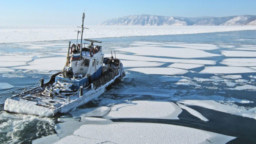 a single ship navigating chunks of ice in the waters of Siberia