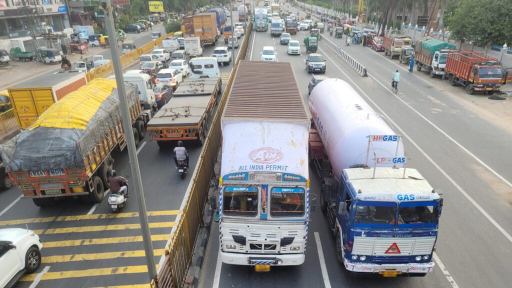 several large trucks and cars on a highway in Agra, India.